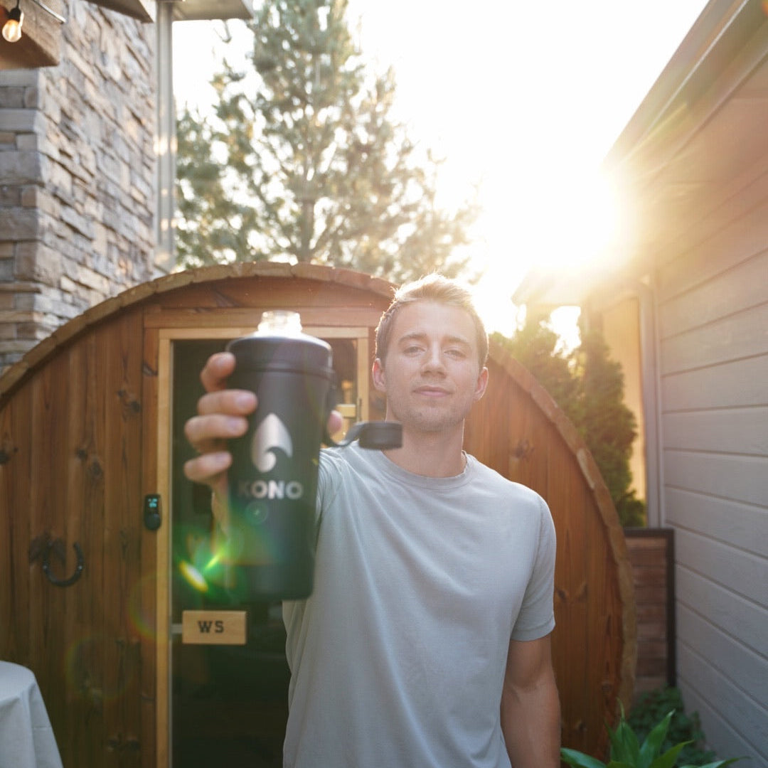recovery scene: KONO shaker raised outside a sauna, casual t-shirt and sunburst in background