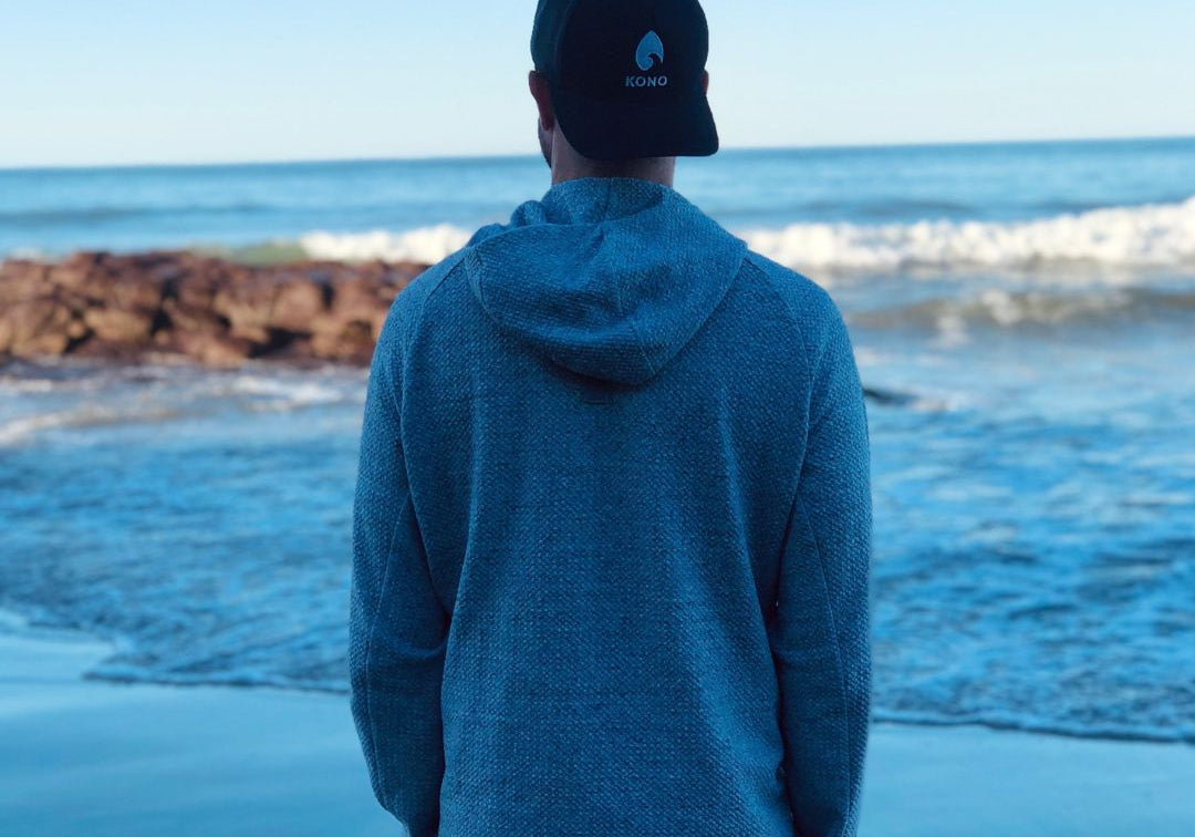 peaceful coastal scene—individual standing near shoreline with rocks and calm surf