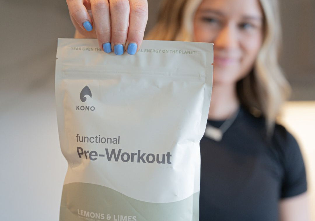 KONO functional pre-workout bag—lemons & limes—held in front of a smiling woman in a kitchen setting