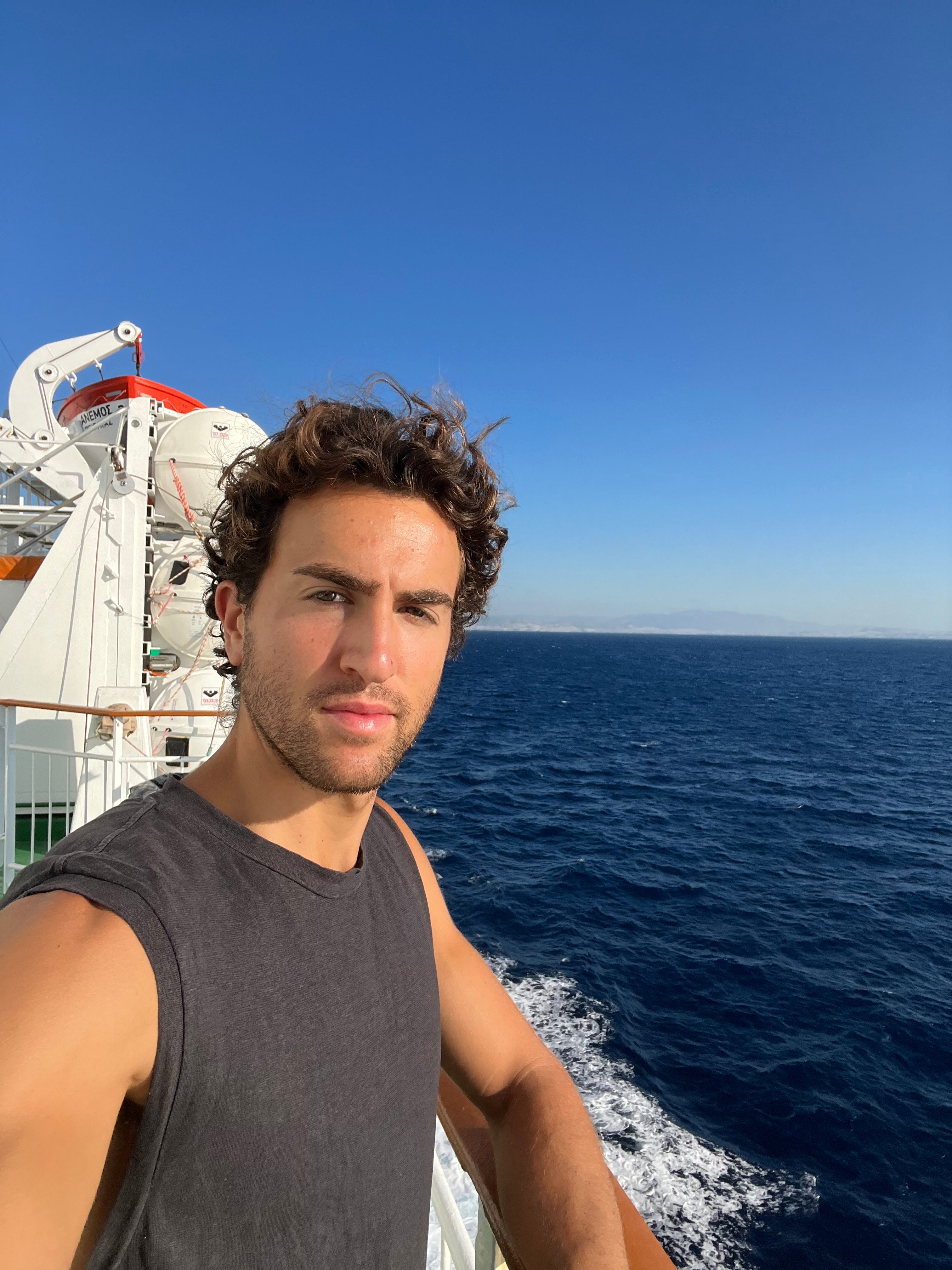 Man standing on a ship deck overlooking the ocean on a clear sunny day