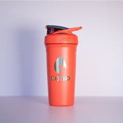 Coral shaker: Coral KONO BlenderBottle shaker bottle with flip cap and silver logo, gym protein shaker product shot on a clean backdrop.