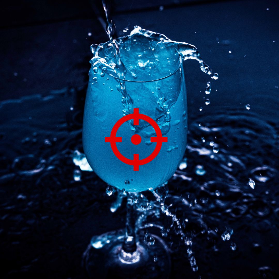 Blue liquid splashing into a glass with water droplets frozen in motion