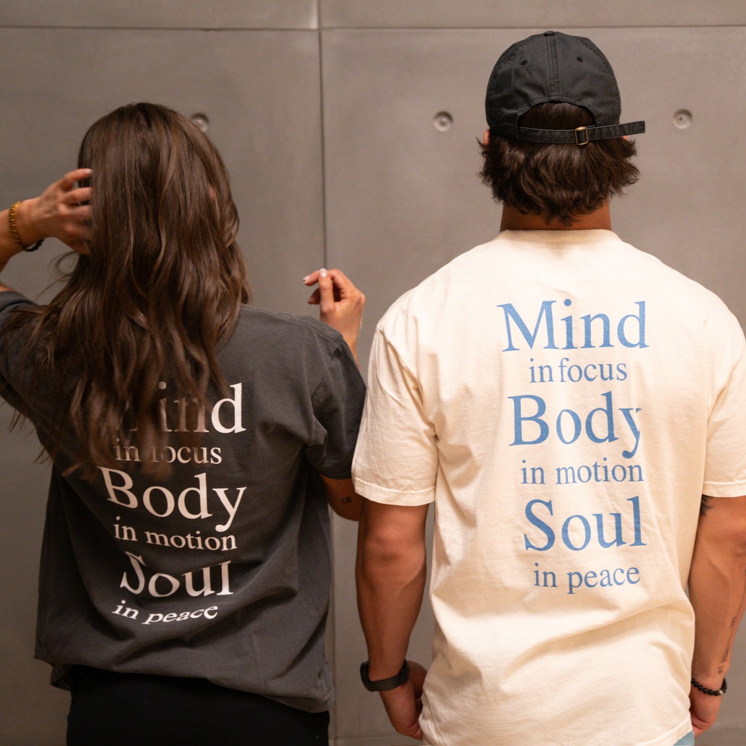 Back view of KONO graphic tees—‘Mind in focus, Body in motion, Soul in peace’ typography print; charcoal and cream shirts, lifestyle shot.