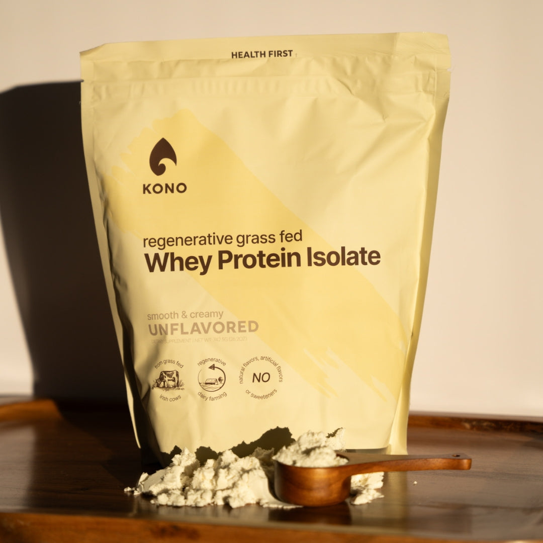 KONO regenerative grass-fed Whey Protein Isolate Unflavored—front pouch with protein powder and wooden scoop on serving tray.