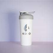 White shaker: White KONO x BlenderBottle protein shaker with gray flip cap and metallic logo, studio product photo on a light background.