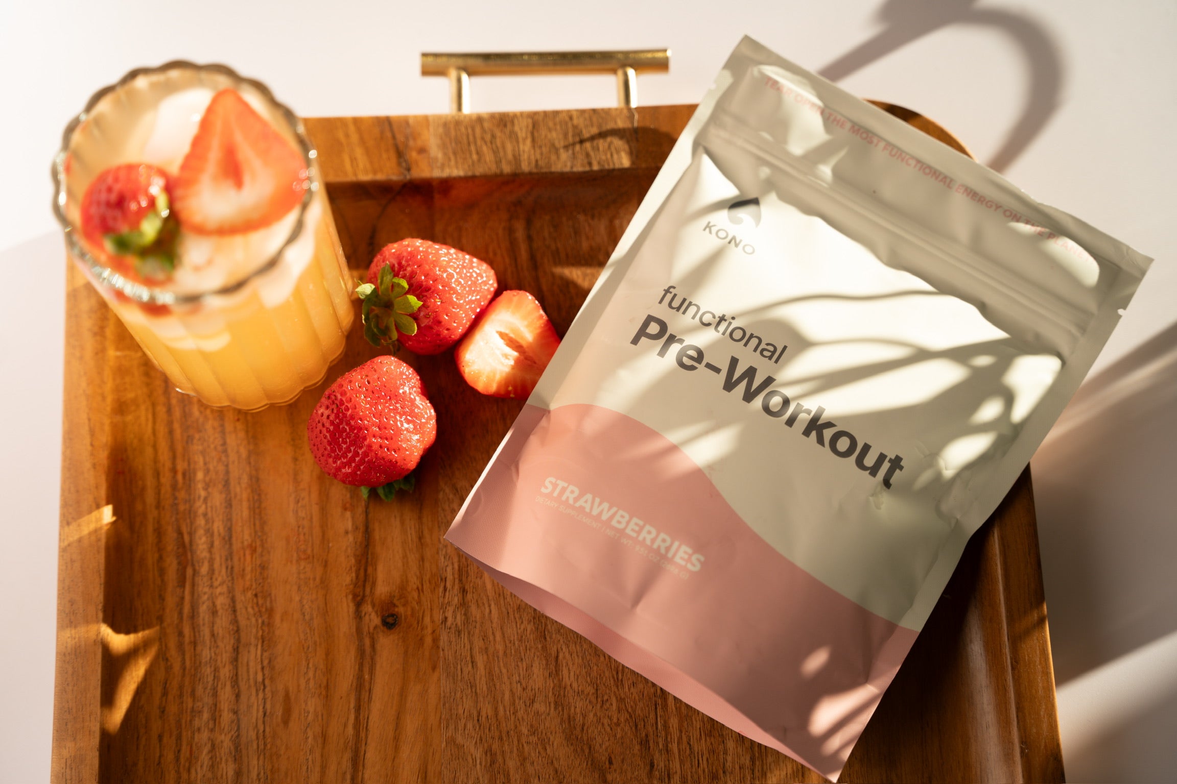 KONO functional pre-workout strawberries flavor on a wooden tray with fresh strawberries and a cold drink